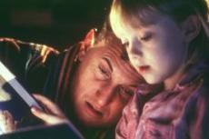 Uma menina e um adulto lendo um livro